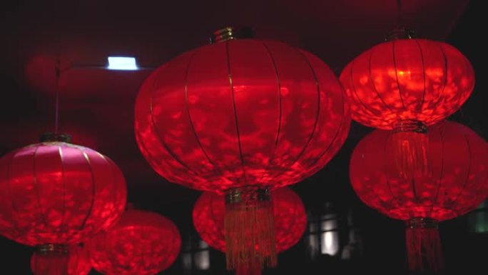 农历新年庆祝活动期间，红色圆形灯笼的特写镜头，里面装有灯泡，在夜间随风摇曳