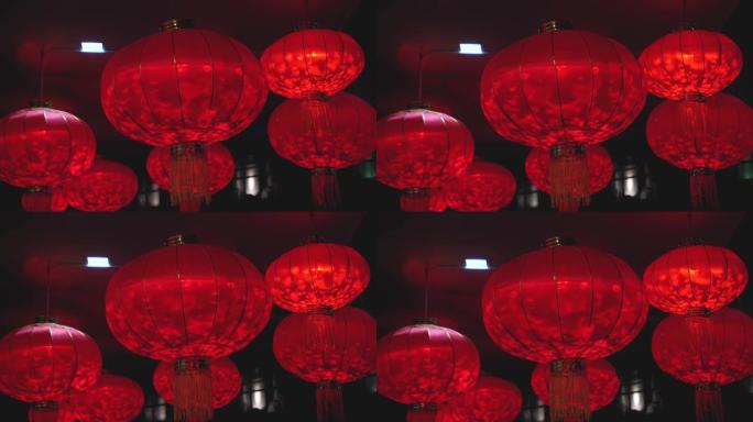 农历新年庆祝活动期间，红色圆形灯笼的特写镜头，里面装有灯泡，在夜间随风摇曳