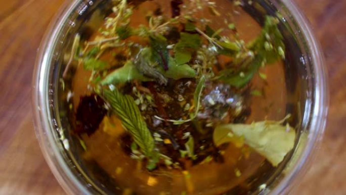 俯视图特写茶叶在透明杯中打开热水。用白开水在杯子里冲泡草本绿色或红茶