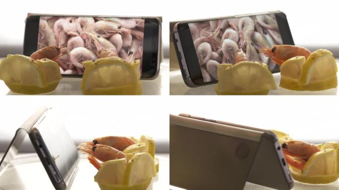 两只冷冻大虾坐在柠檬椅上观看手机屏幕上的煮虾食谱视频。