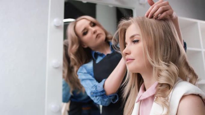 专业发型师整理造型发型年轻女孩客户。红色相机上的中等镜头