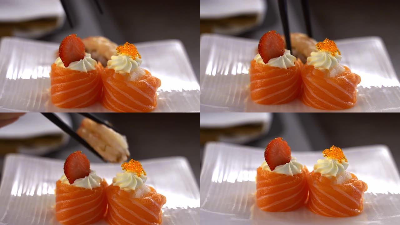 日本餐厅开胃寿司卷特写。新鲜的鲑鱼片，配以原始的费城奶酪，草莓和鱼子酱。日本筷子健康饮食，东方美食概