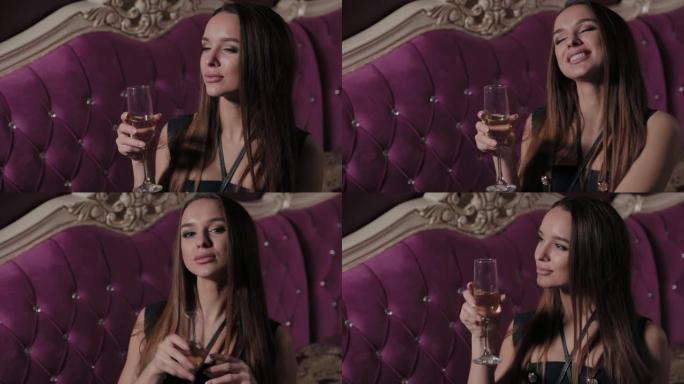 美丽的年轻女子在餐厅内部喝一杯香槟
