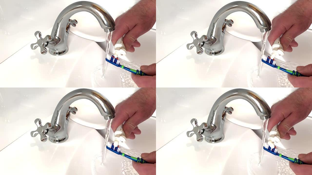 男人挤压小管，将牙膏放在刷子上，将其放在水槽上，水从水龙头流出。用刷子和牙膏管近距离观察人的手