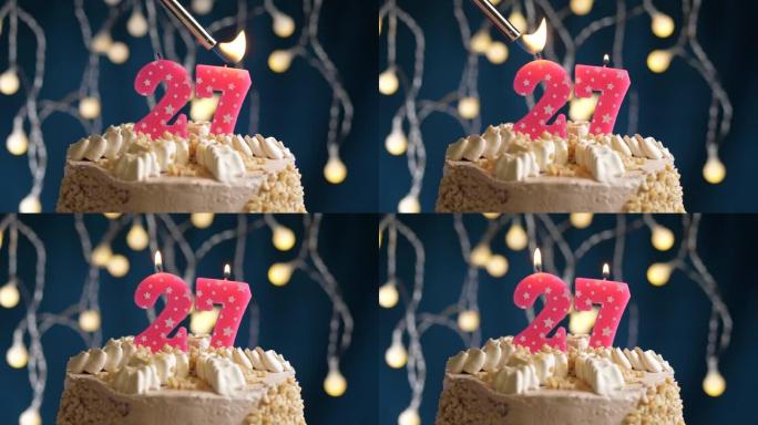蓝色背景上有27个粉色蜡烛的生日蛋糕。蜡烛着火了。慢动作和特写视图
