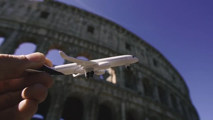 旅程。一架玩具飞机在历史悠久的体育馆大楼的背景下飞行。罗马。意大利。
