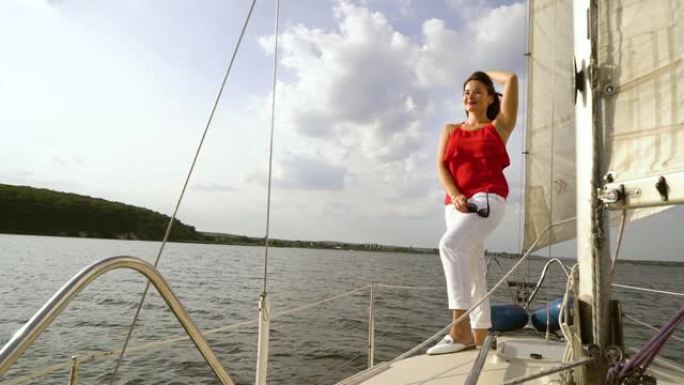 穿着红色和白色衣服的微笑女人在帆船上放松