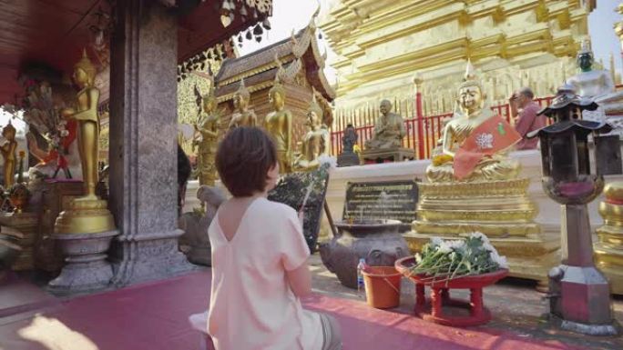 亚洲妇女在寺庙中与佛陀祈祷