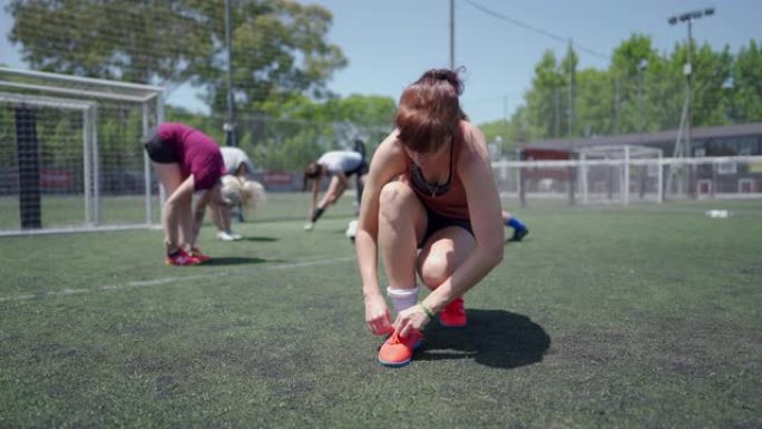 女子足球运动员在足球场上系鞋带