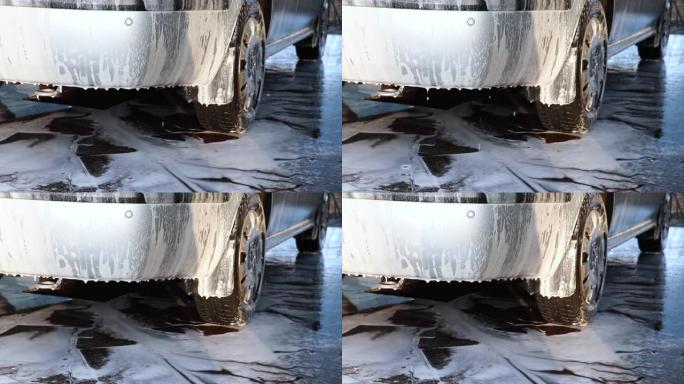大液滴的泡沫从灰色机器上流失，以清洁机器上的污垢。汽车零件上的白色泡沫液滴的宏观视频。