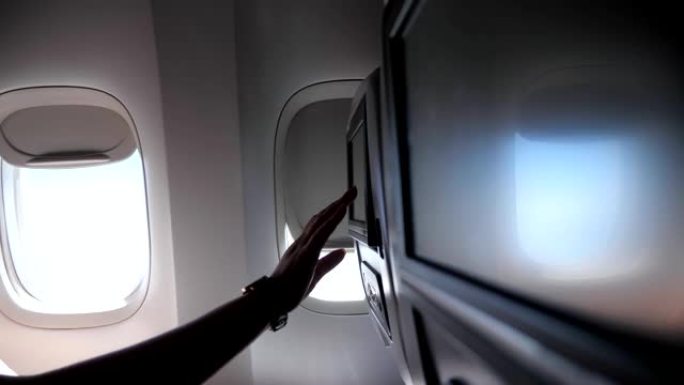 女性手触摸飞机特写中的座椅靠背屏幕