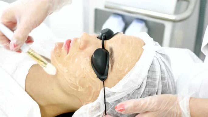 治疗师在女性客户脸上涂抹特殊药膏
