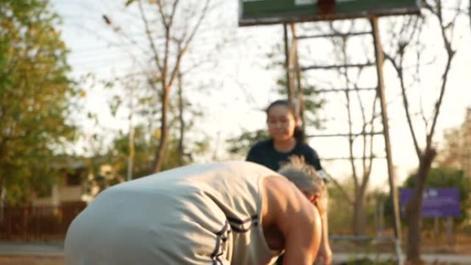 亚洲资深父亲在夏日与女儿在体育场打篮球。幸福的家庭一起度过空闲时间。健康的生活方式理念。