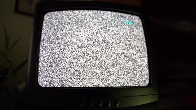 老式复古电视晚上在家庭房间工作，老式电视有噪音静电。在旧电视设备上更改电视频道，屏幕上出现黑白故障。