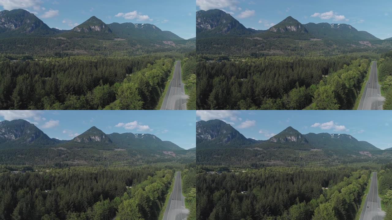 华盛顿州金条附近山区之间森林中繁忙的2号高速公路的鸟瞰图。无人机视频与上升的摄像机运动。