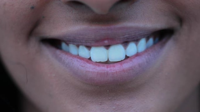 女孩嘴巴微笑的特写。漂亮的非洲裔美国年轻女子嘴唇裂开微笑