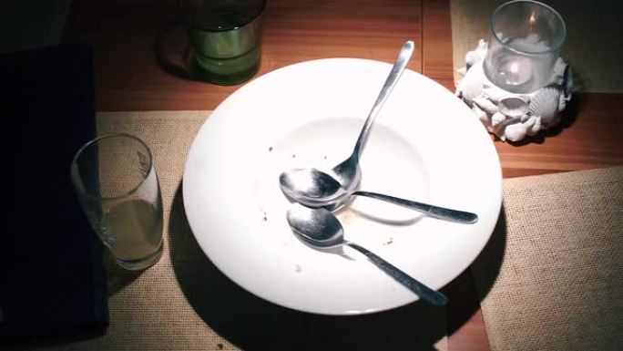 餐厅桌子上空盘子里的三把勺子