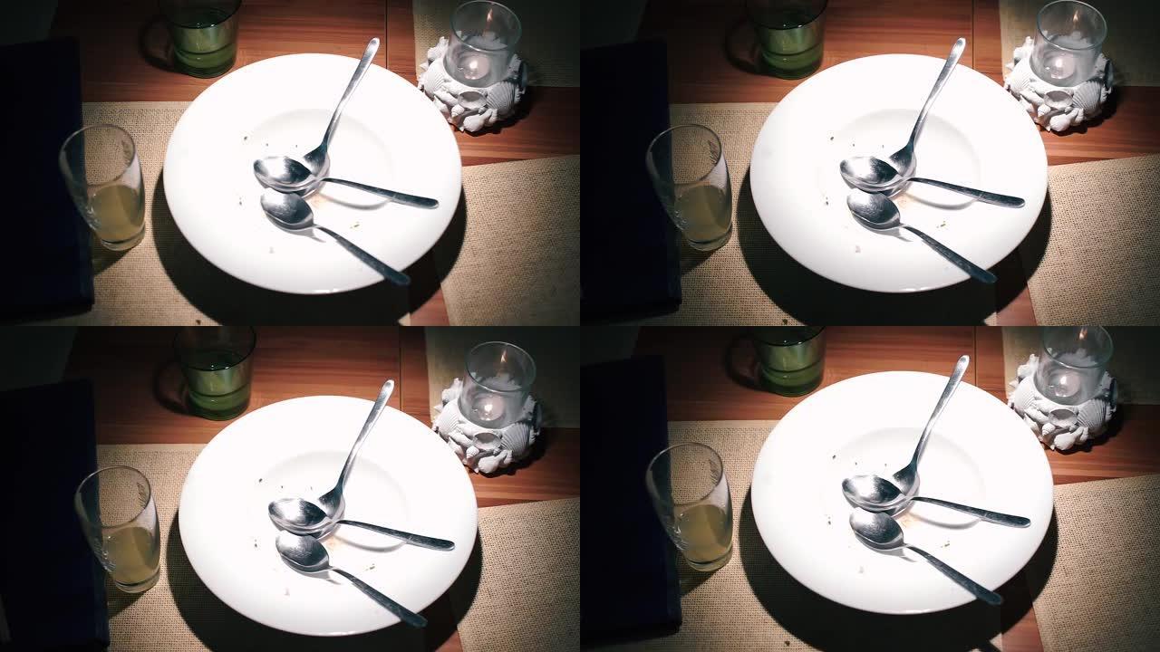 餐厅桌子上空盘子里的三把勺子