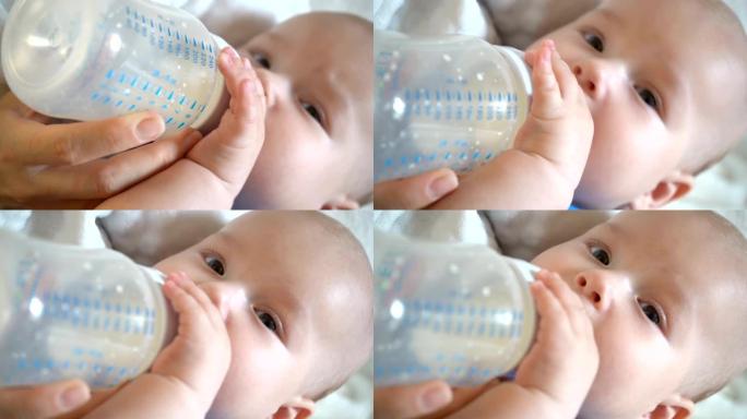 可爱的男婴抱着瓶子，从瓶子里喝牛奶，4K