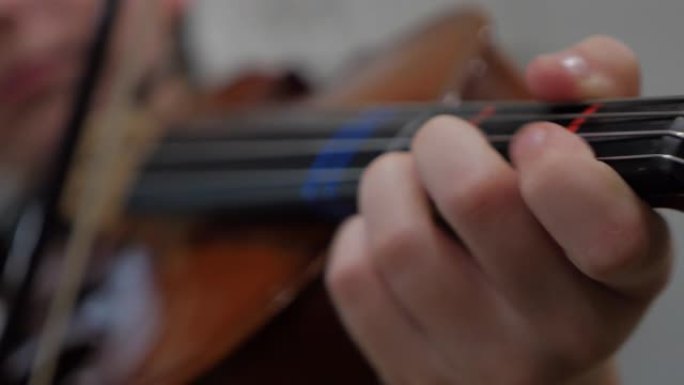 一个小男孩的手指拉小提琴的特写
