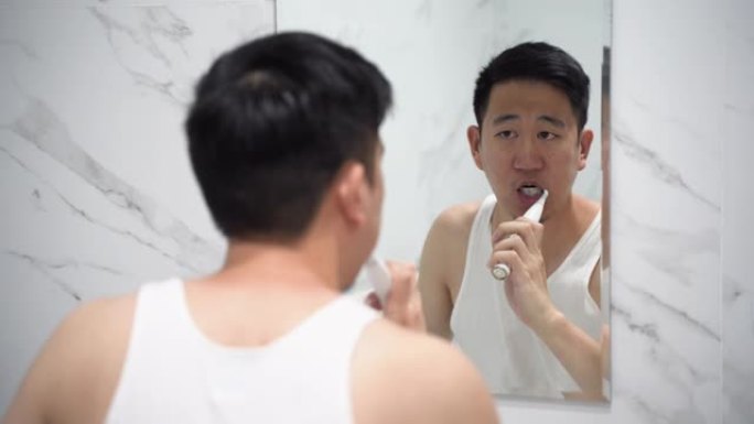 亚洲男子使用电动牙刷清洁牙齿