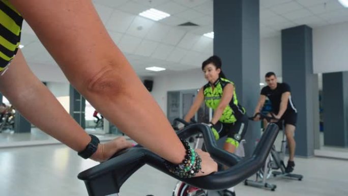 在健身房俱乐部的自行车课上锻炼自行车的女人。团体健身人士训练自行车运动。健身课上的自行车训练。静态自