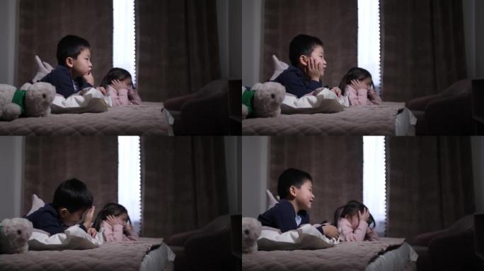 可爱的中国兄弟姐妹躺在床上看电视