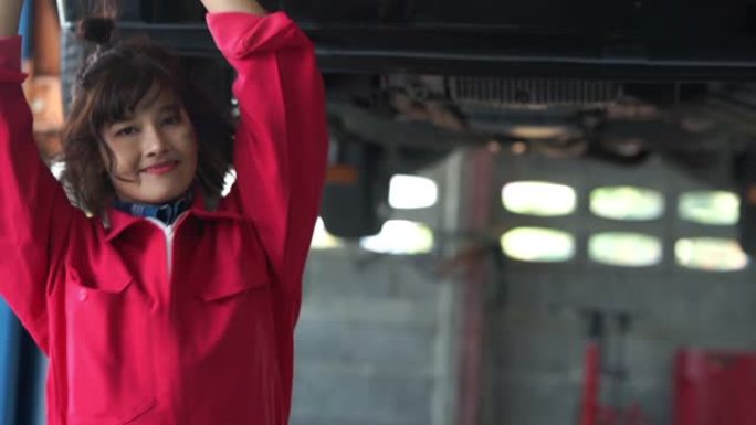 年轻的女技术员在车库里开心地微笑和跳舞，一整天的努力工作后放松