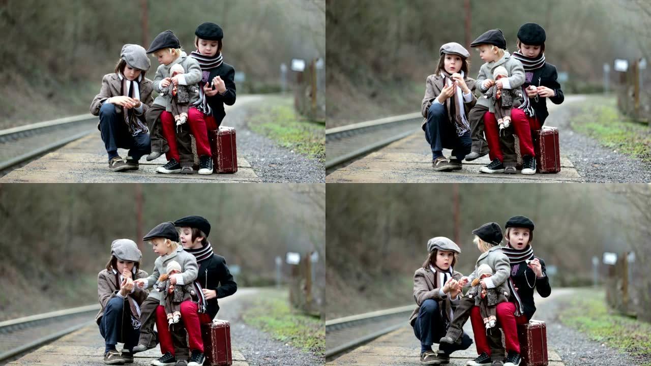 火车站上可爱的boy，带着手提箱和漂亮的老式娃娃等着火车