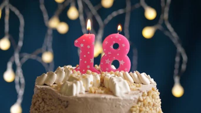 蓝色背景上有18号粉色蜡烛的生日蛋糕。蜡烛吹灭了。慢动作和特写视图