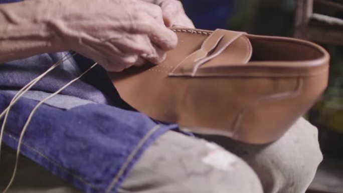 高级鞋匠坐在车间手工制作鞋子。