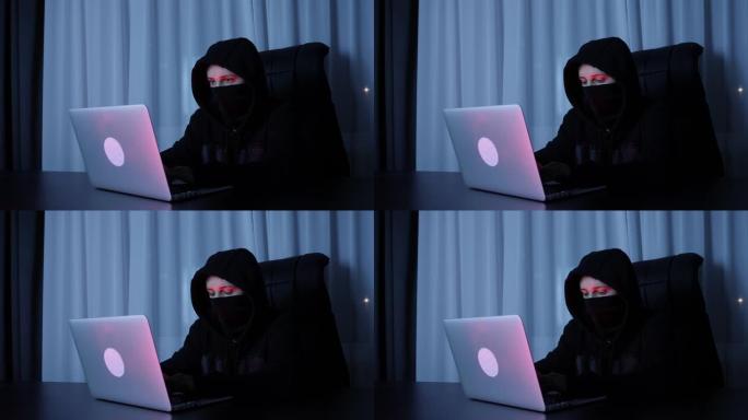 女黑客坐在黑暗的房间里，在笔记本电脑键盘上打字。女人在屏幕上戴着黑色面具和引擎盖编码，并打破密码。专