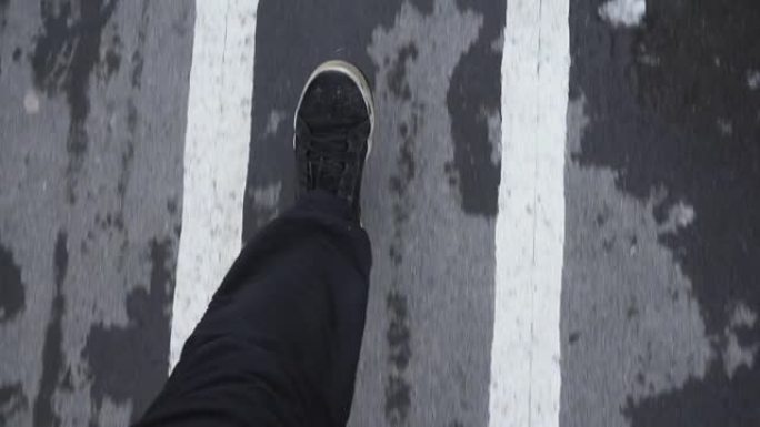 在湿沥青人行道上行走自由的概念。穿着运动鞋往下看