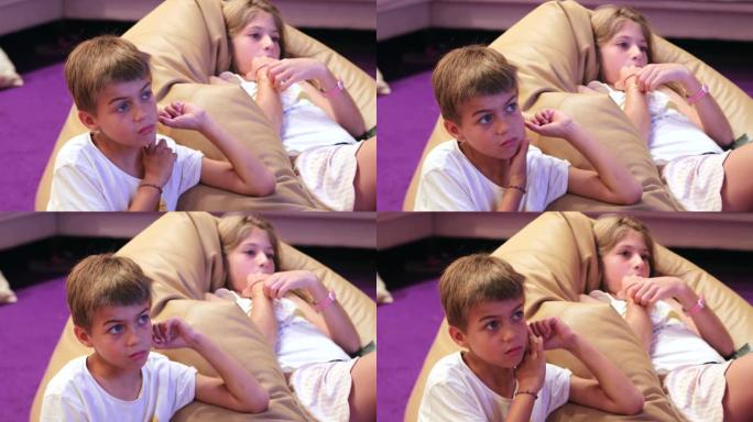 坦率的孩子在客厅看电视屏幕，坐在沙发上的孩子