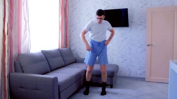 有趣的书呆子男人正在家里做前坡和腿部伸展运动。运动幽默概念。