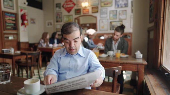 在咖啡店里喝咖啡休息时侏儒的成年男子看报纸