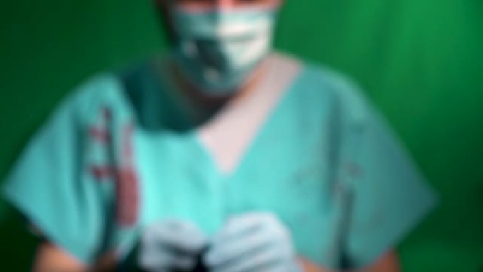 无法辨认的散焦外科医生医生长袍覆盖着血液，戴着手套服用橙色药丸