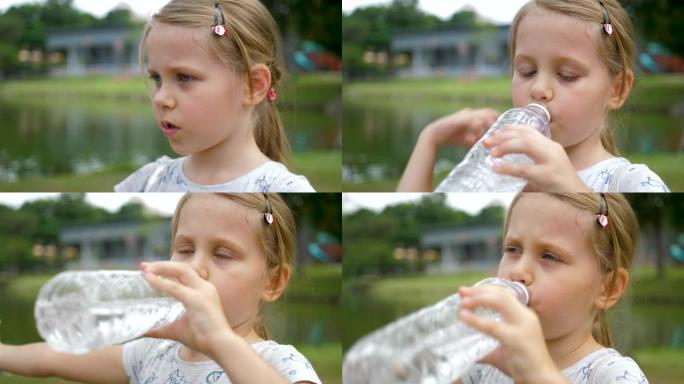 可爱的女孩孩子用塑料瓶喝水