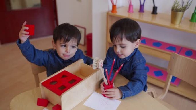 可爱的双胞胎男孩在幼儿园教室里一起玩耍