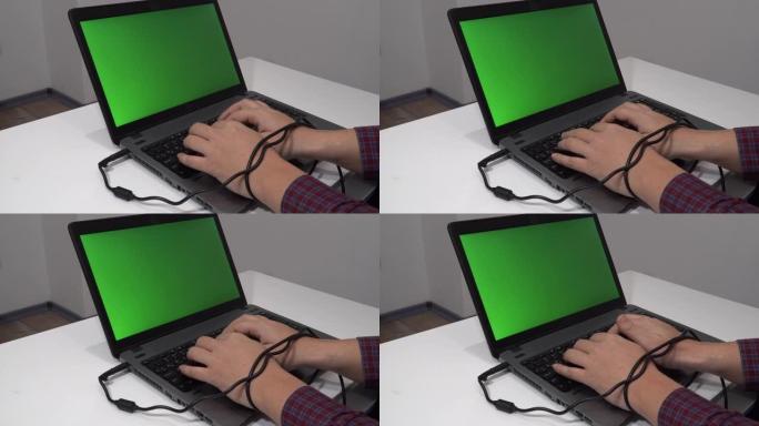 现代问题概念。男子在笔记本电脑上打字，双手纠结在电缆中
