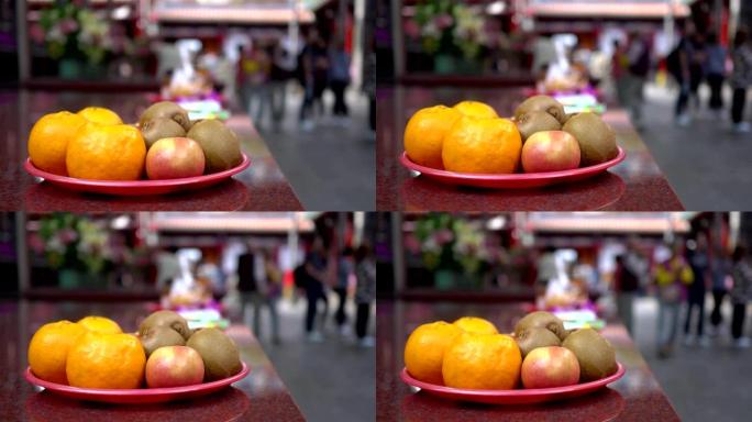 亚洲寺庙中供奉的水果。模糊的背景是朝拜者经过。