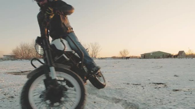 摩托车手在雪地里做轮胎倦怠，慢动作。专业摩托车手在日落时在雪地上漂移并打开摩托车。骑自行车的人在摩托