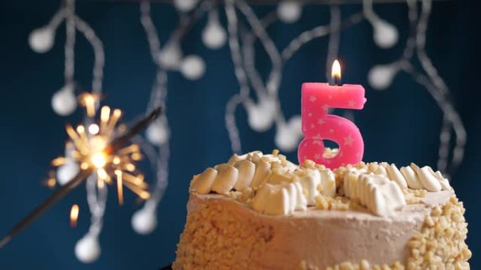 生日蛋糕，蓝色背景上有5个数字粉色蜡烛和烟火。慢动作和特写视图
