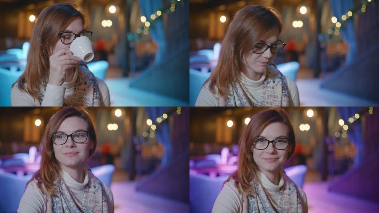戴着眼镜的美丽微笑女孩的肖像使用智能手机与社交网络上的朋友聊天，在昂贵的体面餐厅放松时喝咖啡