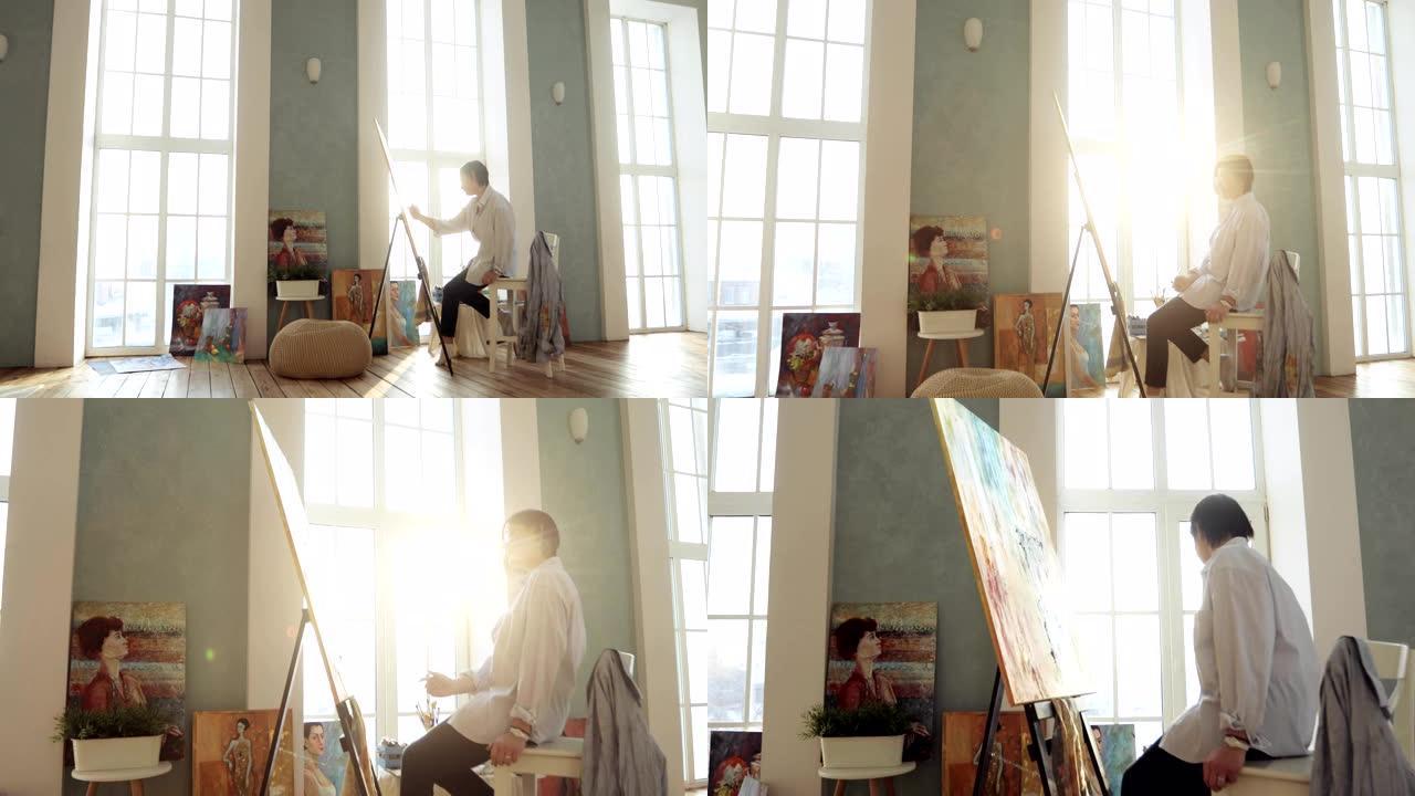 Painttress绘画图片坐在窗户附近的艺术工作室中，相机放大