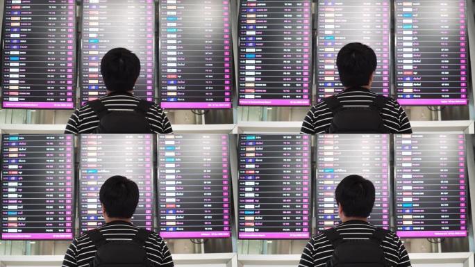 亚洲男子在机场到达离境板寻找登机口。