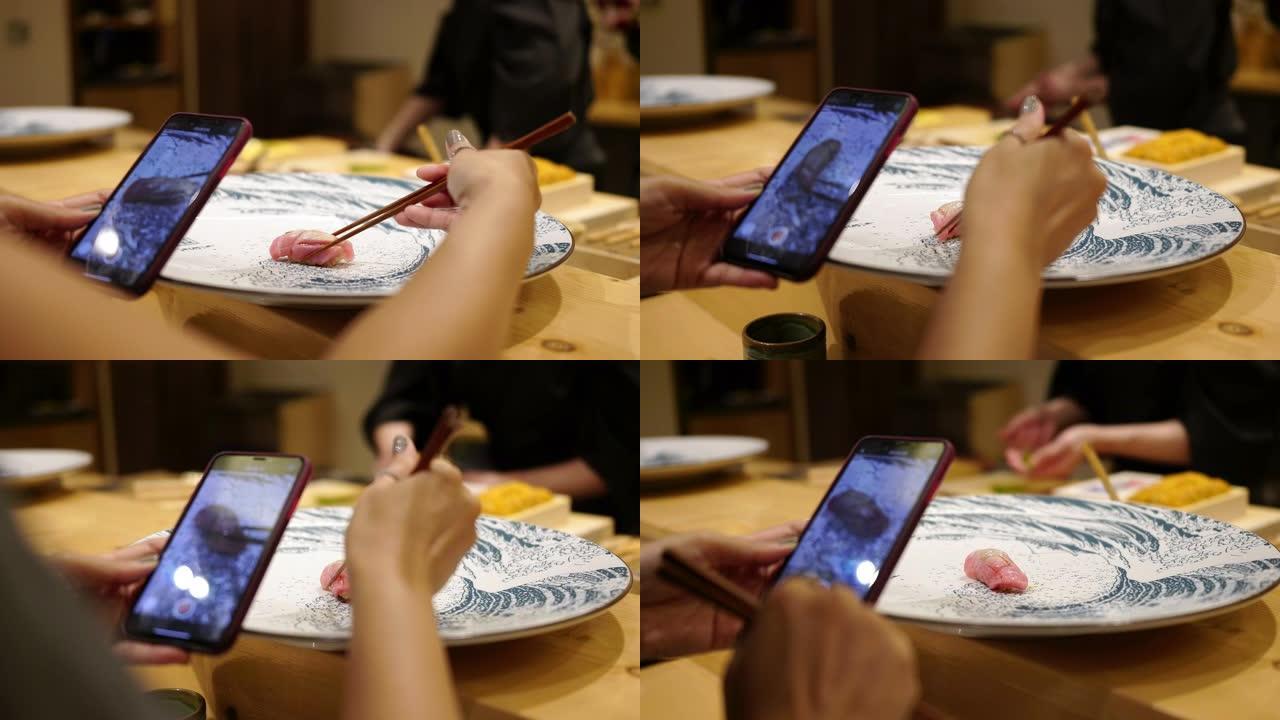 一名妇女在一家日本小餐馆里用智能手机拍摄寿司的照片