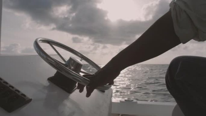 一只手放在小船的方向盘上。