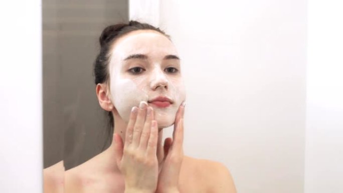 快乐迷人的年轻女子用洁面乳洗脸。