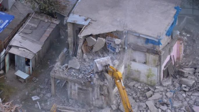 在施工现场使用推土机的机械臂摧毁旧混凝土房屋